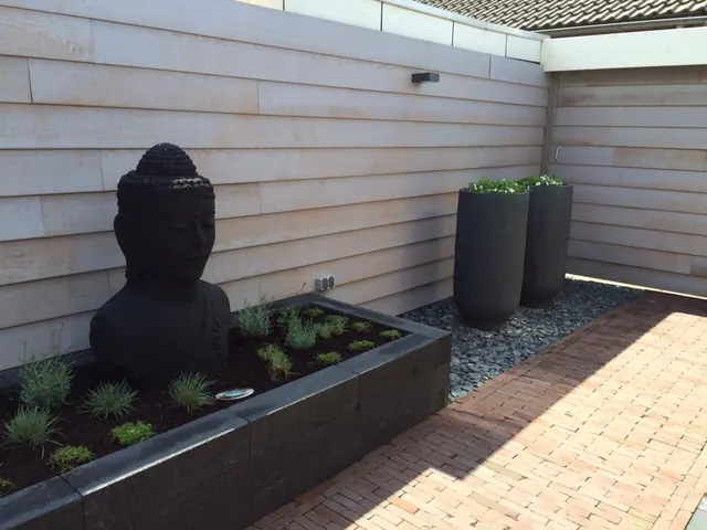 Verhoogde border met een Boeddhabeeld, grind en klinkers