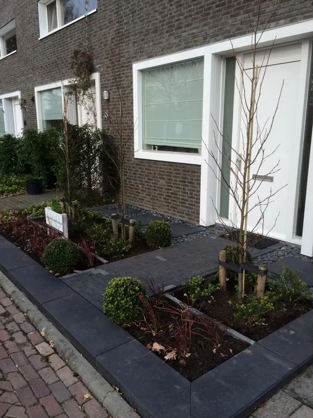 Strakke voortuin met antracieten opsluitbanden en beplanting